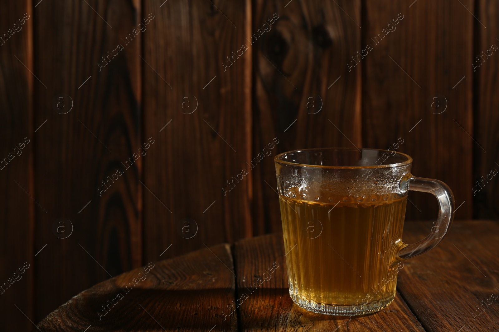 Photo of Refreshing green tea in cup on wooden table, closeup. Space for text