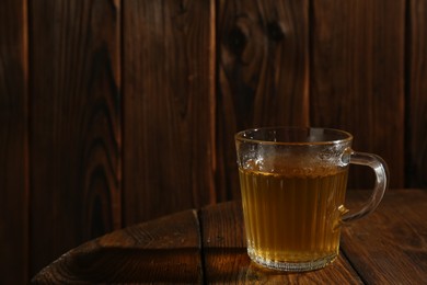 Photo of Refreshing green tea in cup on wooden table, closeup. Space for text