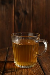 Photo of Refreshing green tea in cup on wooden table, closeup