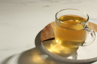 Photo of Refreshing green tea in cup on white marble table, closeup. Space for text