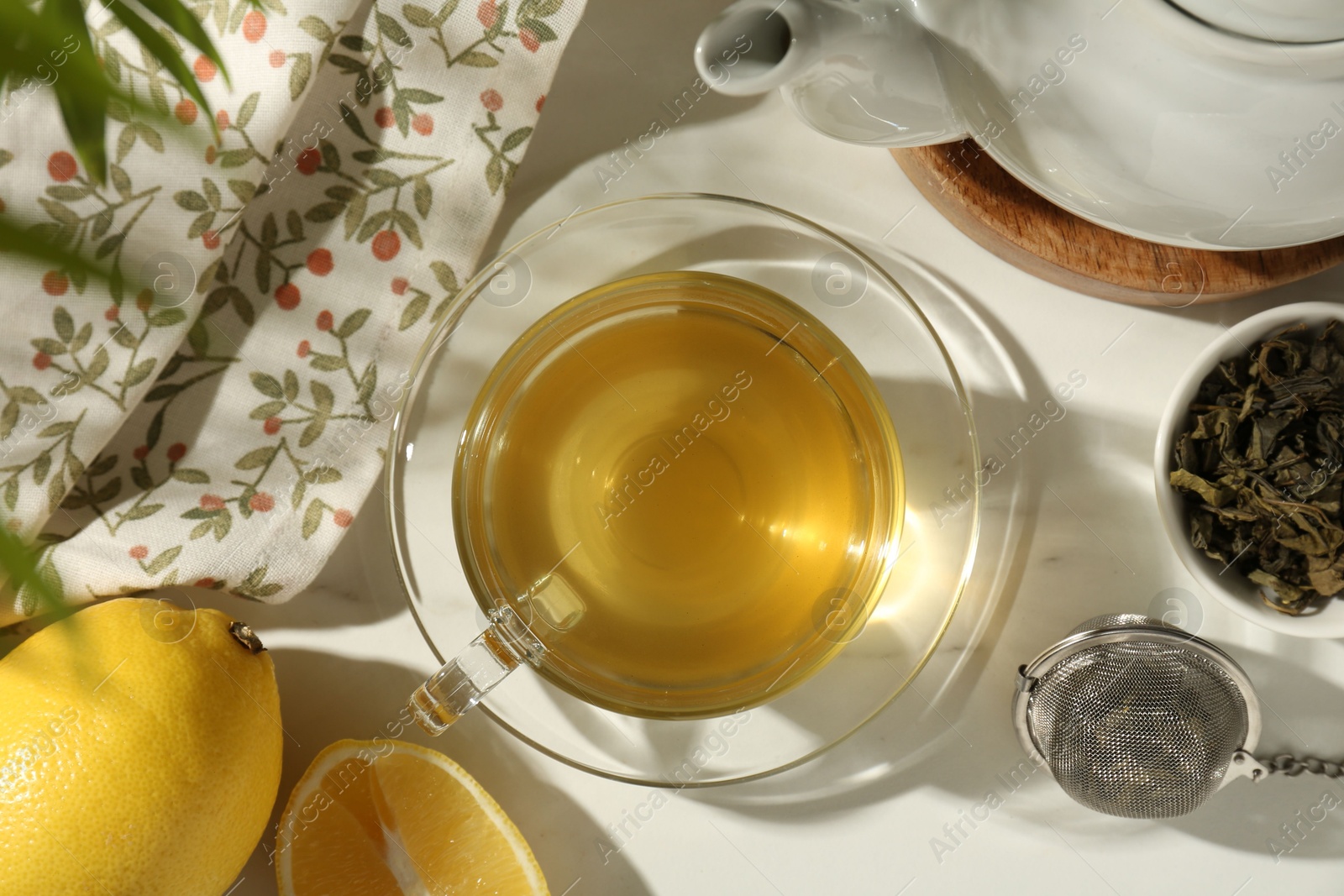 Photo of Flat lay composition with refreshing green tea in cup, dry leaves and cut lemon on white table