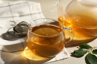 Photo of Refreshing green tea, strainer and leaves on textured table, closeup