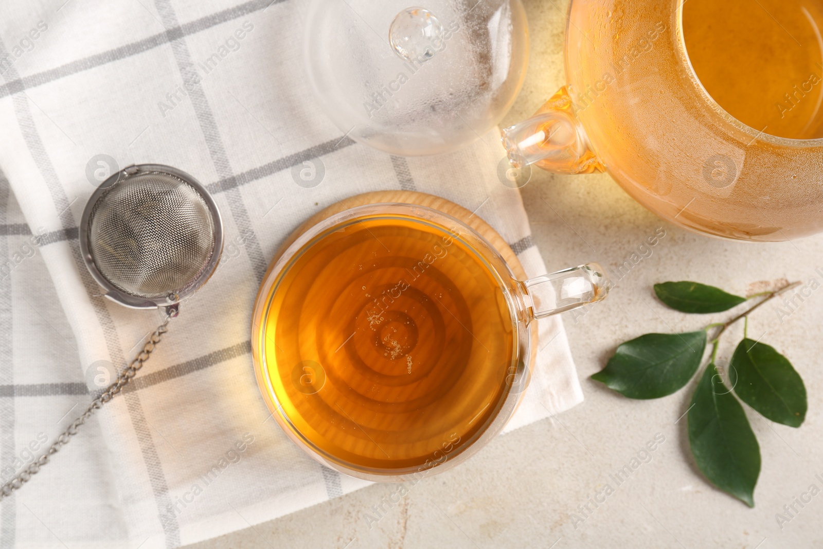 Photo of Refreshing green tea, strainer and leaves on textured table, flat lay