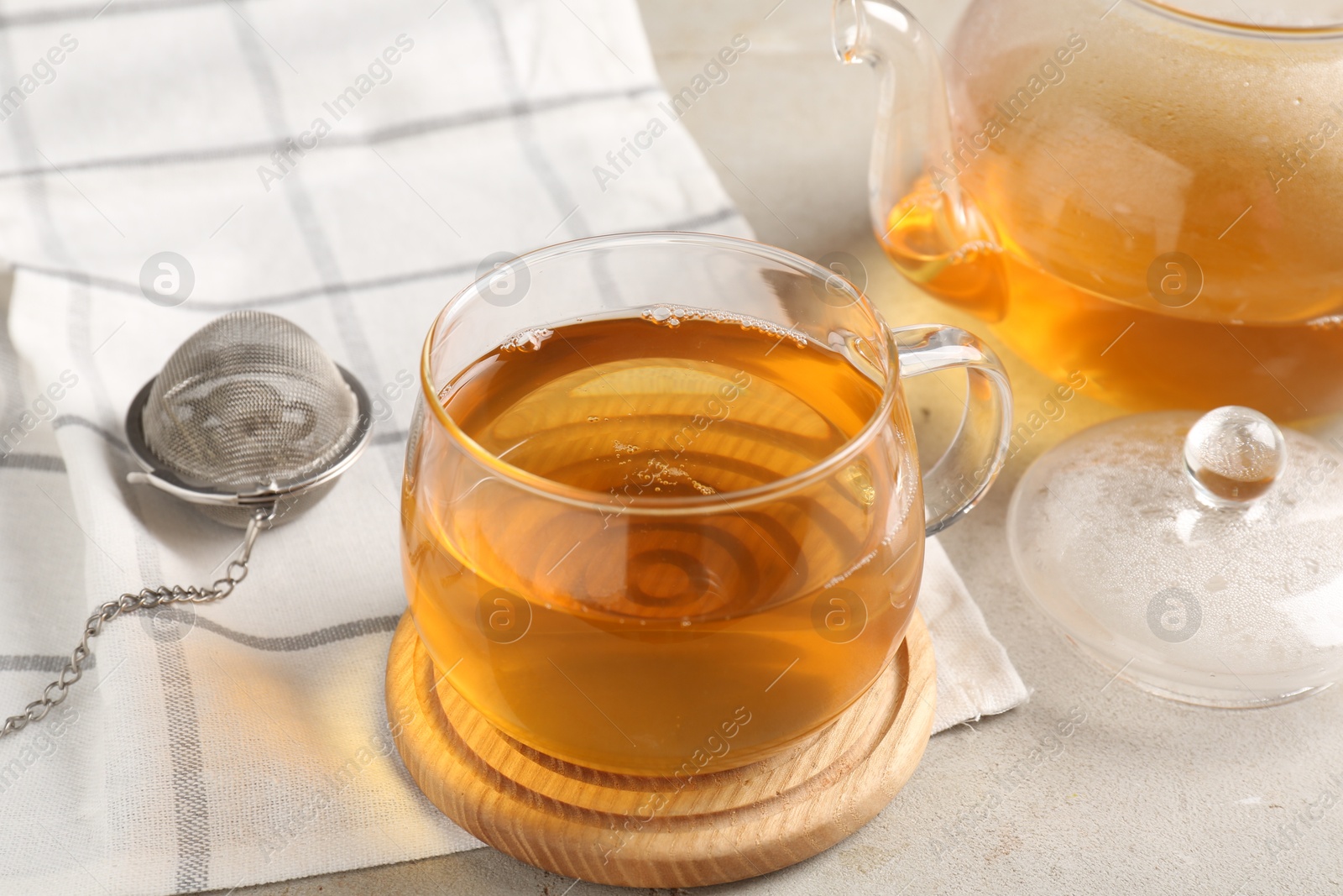 Photo of Refreshing green tea and strainer on textured table, closeup