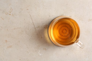 Photo of Refreshing green tea in cup on light textured table, top view. Space for text