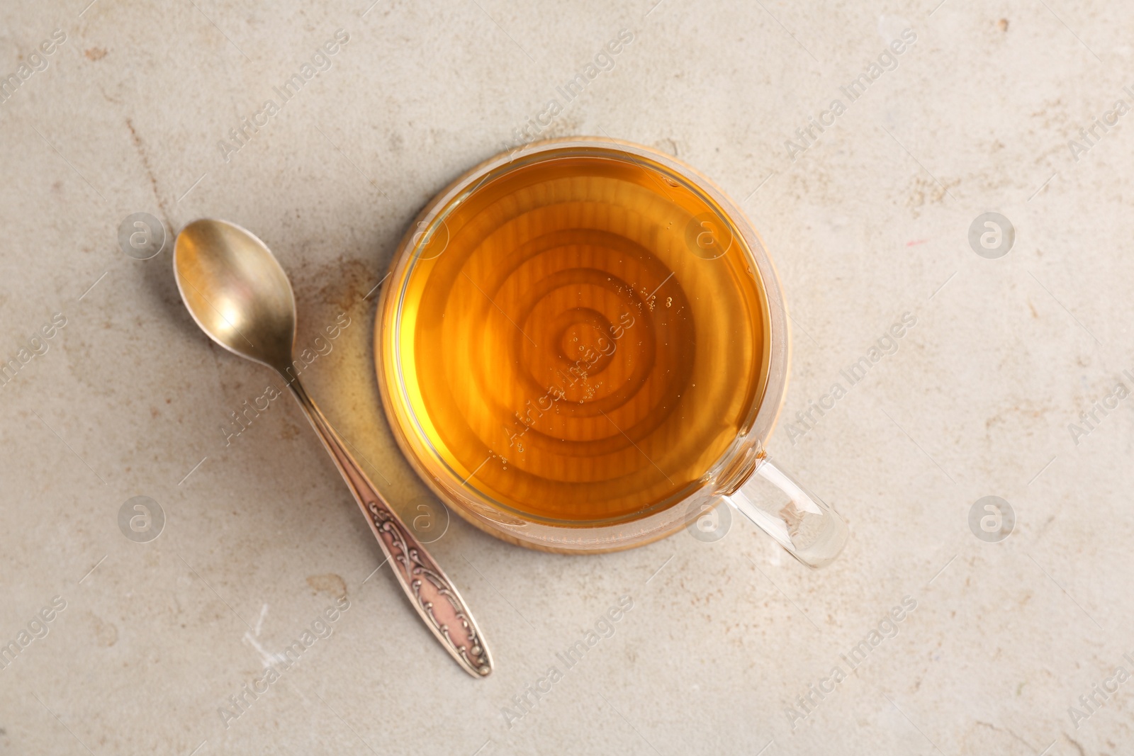 Photo of Refreshing green tea in cup and spoon on light textured table, top view