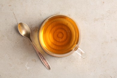 Photo of Refreshing green tea in cup and spoon on light textured table, top view