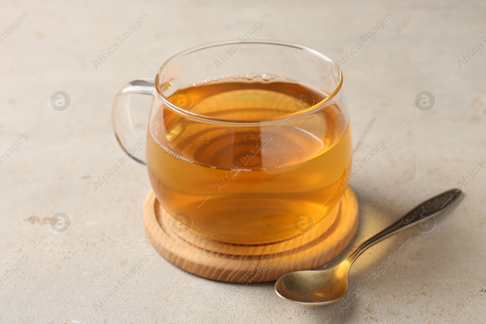 Photo of Refreshing green tea in cup and spoon on light textured table, closeup