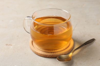 Photo of Refreshing green tea in cup and spoon on light textured table, closeup