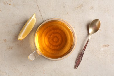 Photo of Refreshing green tea, slice of lemon and spoon on light textured table, flat lay