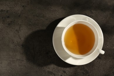 Photo of Refreshing green tea in cup on dark textured table, top view. Space for text