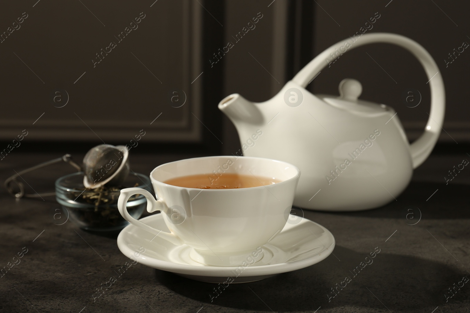 Photo of Refreshing green tea in cup on dark textured table