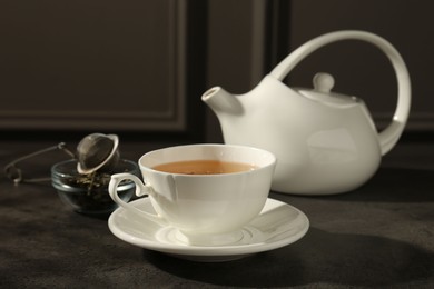 Photo of Refreshing green tea in cup on dark textured table