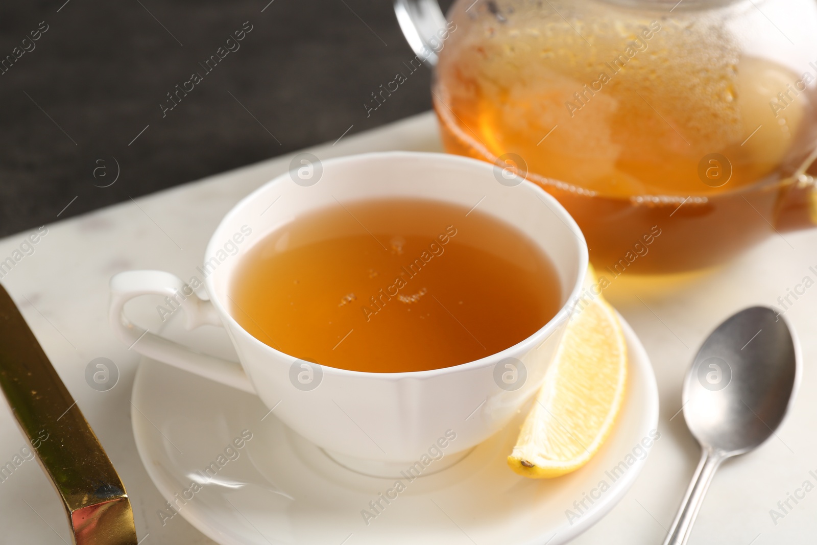 Photo of Refreshing green tea, spoon and slice of lemon on dark table, closeup