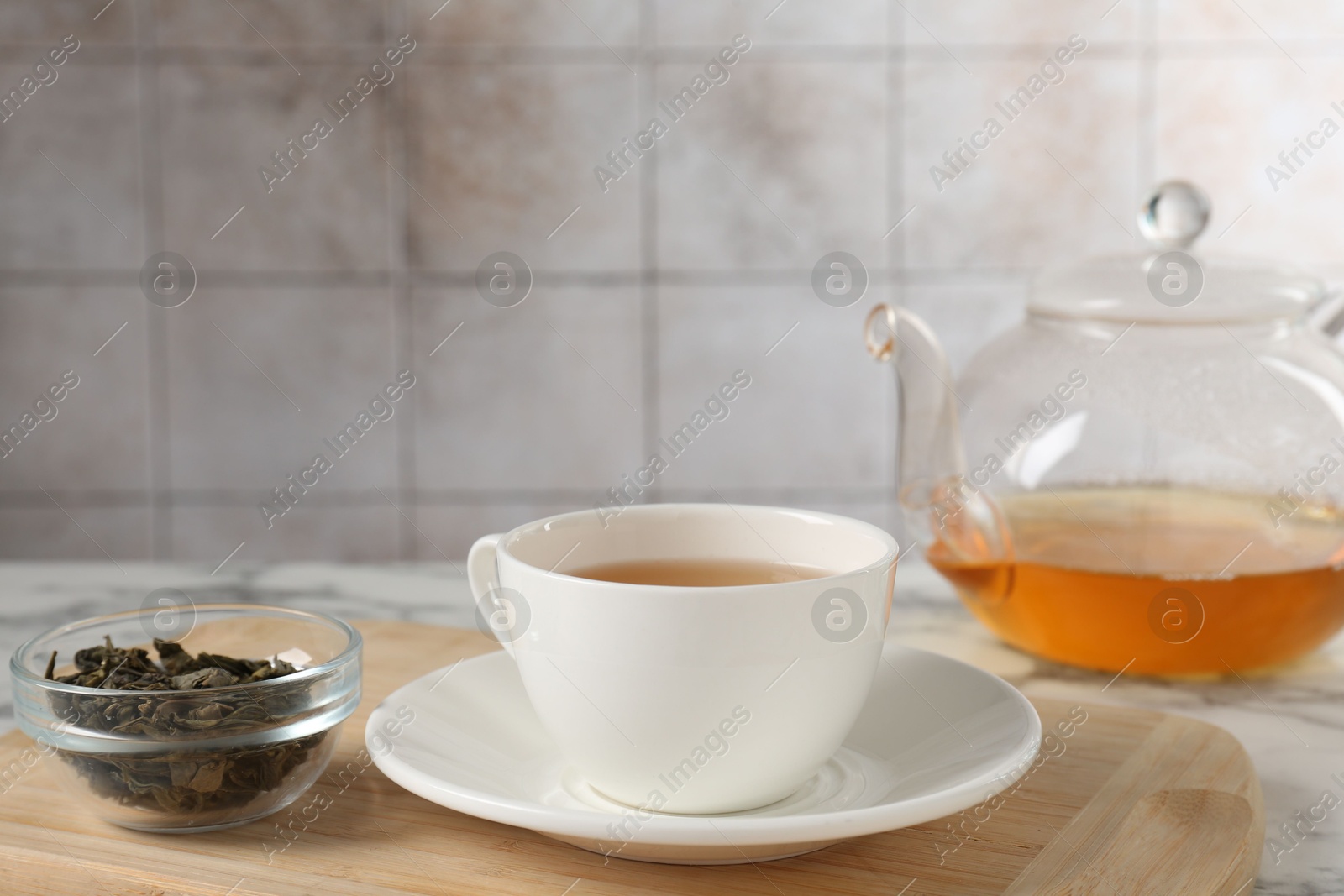 Photo of Refreshing green tea and dry leaves on white marble table, closeup