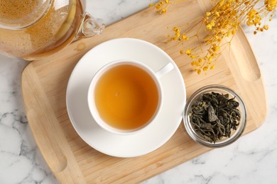 Photo of Refreshing green tea and dry leaves on white marble table, flat lay