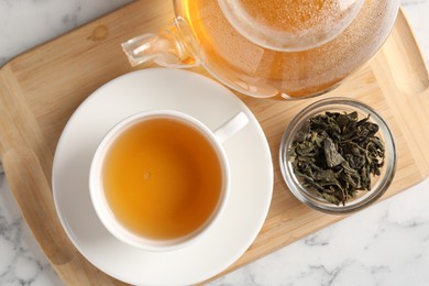 Photo of Refreshing green tea and dry leaves on white marble table, flat lay