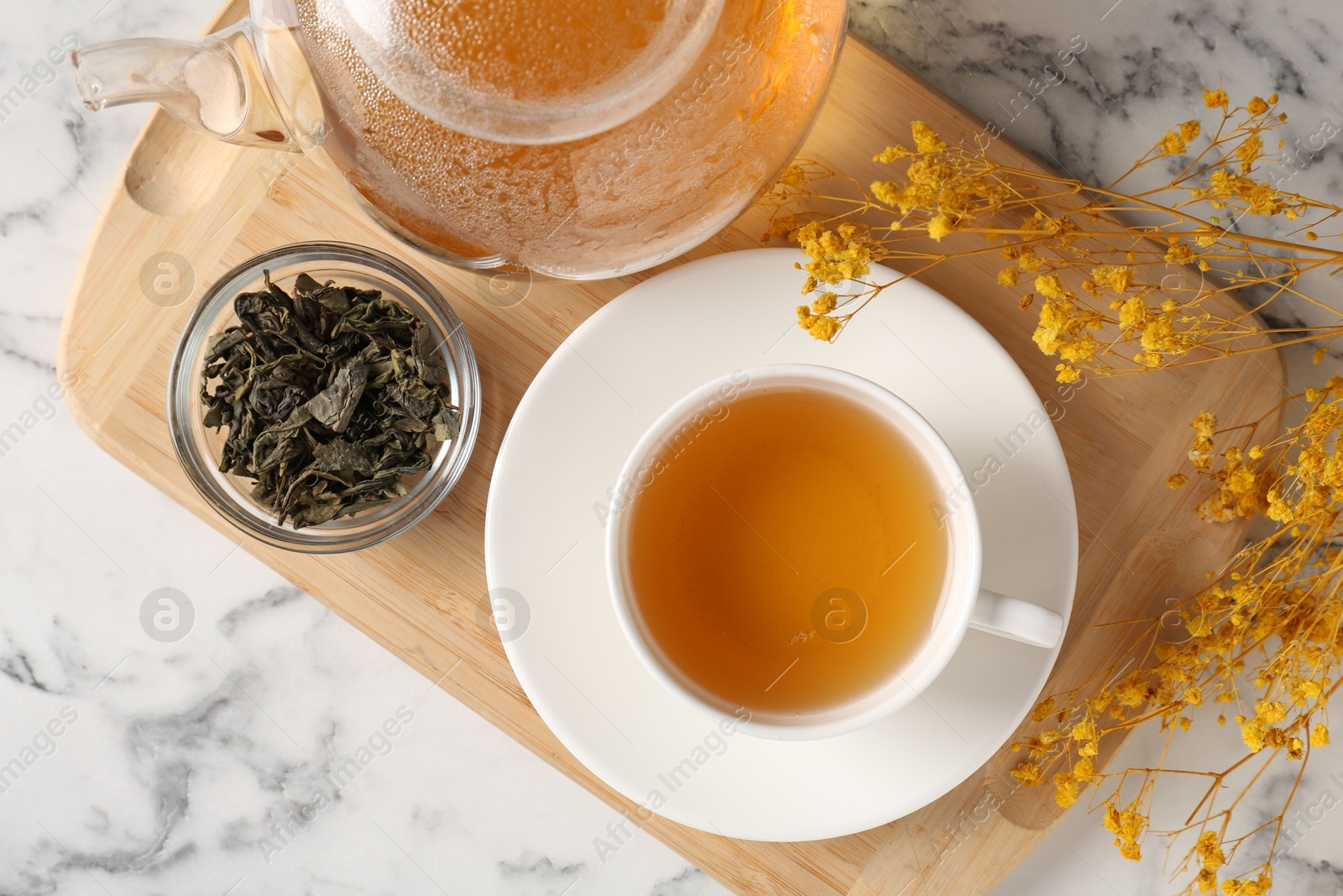 Photo of Refreshing green tea and dry leaves on white marble table, flat lay