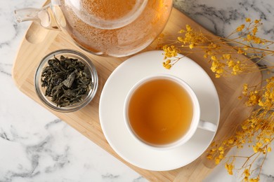 Photo of Refreshing green tea and dry leaves on white marble table, flat lay