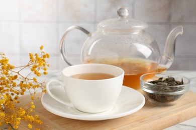 Photo of Refreshing green tea and dry leaves on white table, closeup