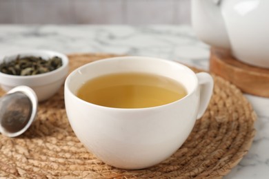 Photo of Refreshing green tea in cup on white marble table, closeup