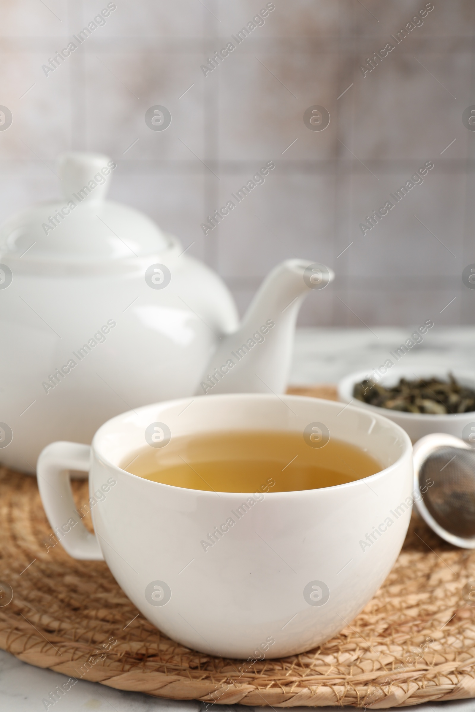 Photo of Refreshing green tea in cup on white table, closeup