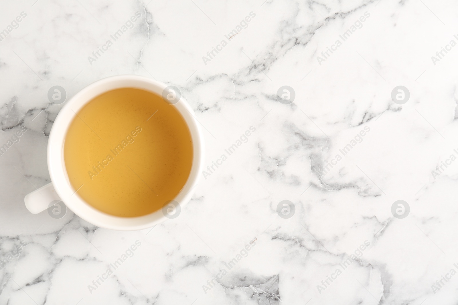 Photo of Refreshing green tea in cup on white marble table, top view. Space for text