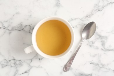 Photo of Refreshing green tea in cup and spoon on white marble table, top view