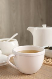 Photo of Refreshing green tea in cup on wooden table, closeup