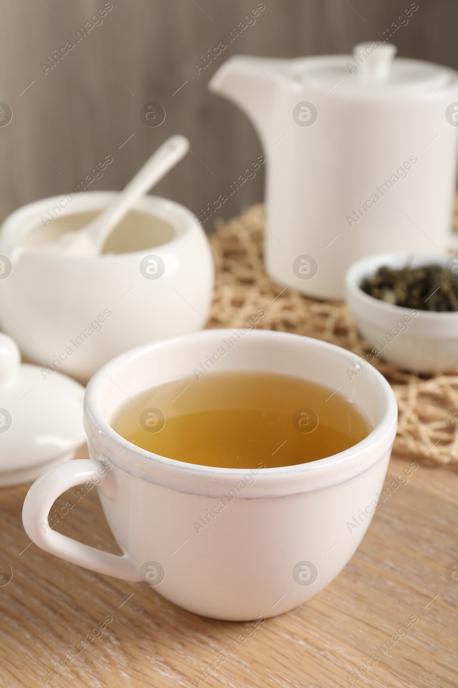 Photo of Refreshing green tea in cup on wooden table, closeup