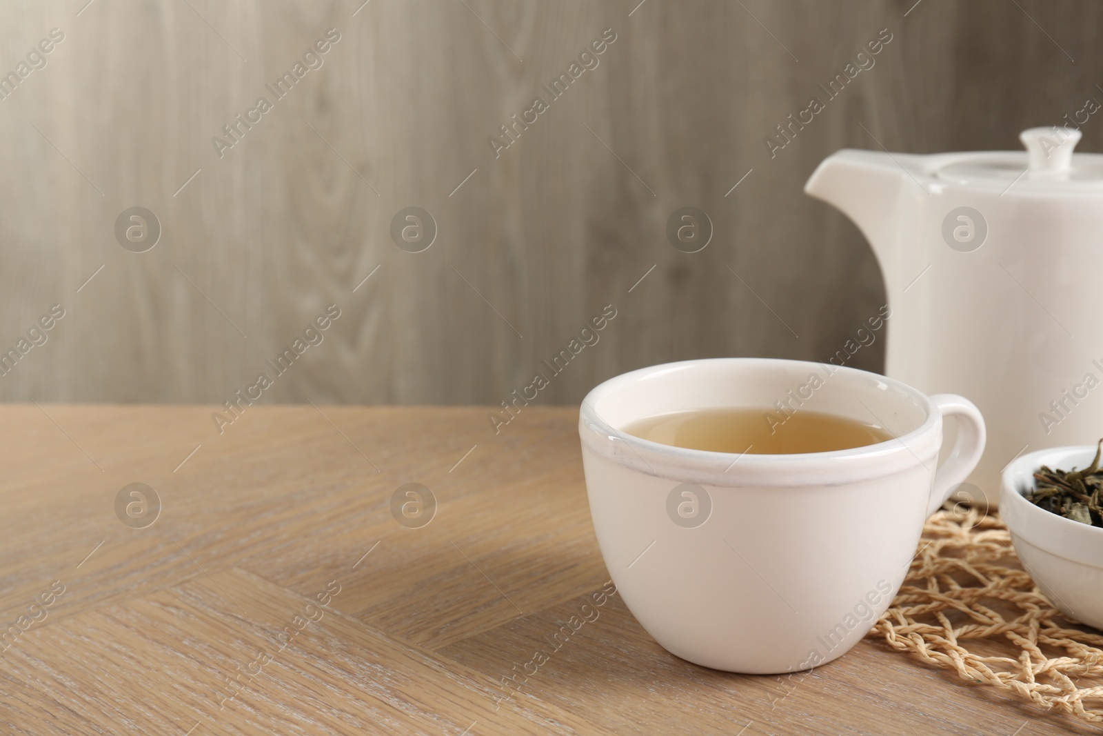 Photo of Refreshing green tea in cup on wooden table, closeup. Space for text