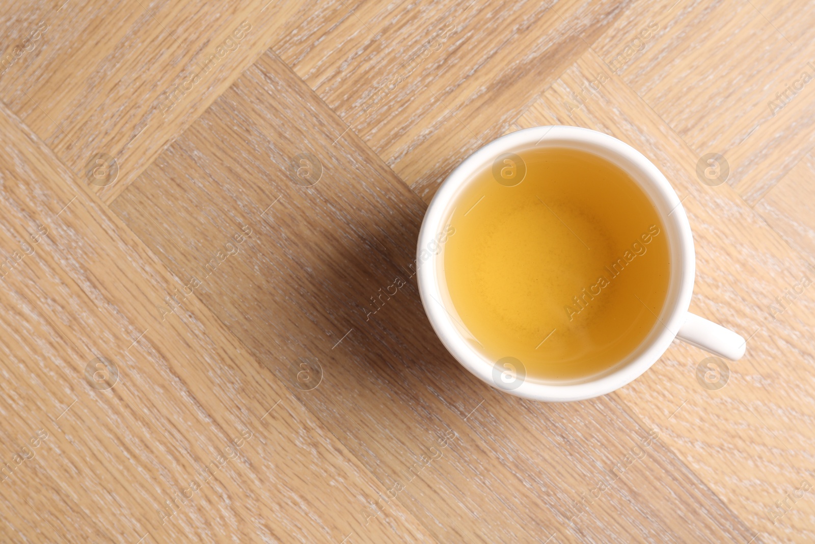 Photo of Refreshing green tea in cup on wooden table, top view. Space for text