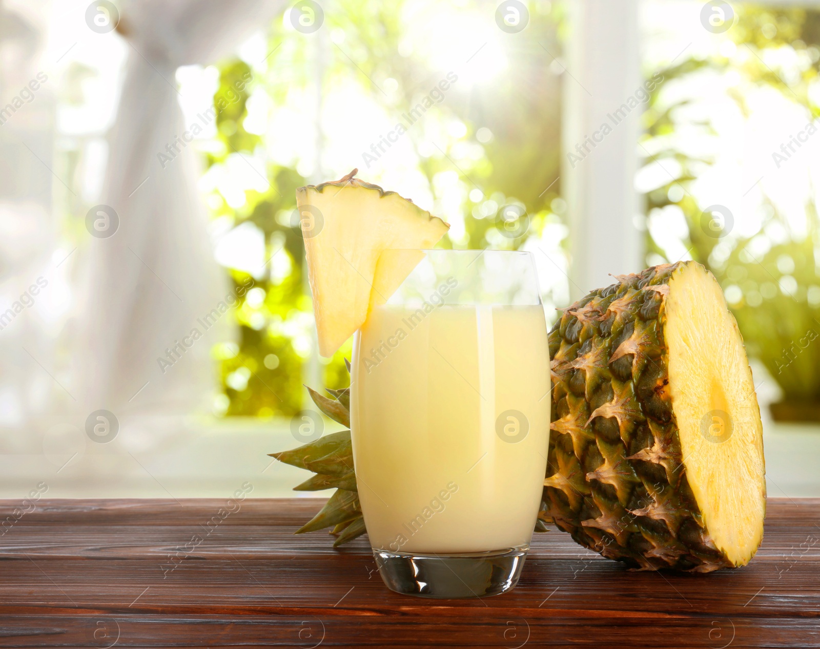 Image of Tasty pineapple cocktail or smoothie in glass and fresh fruit on wooden table indoors. Space for text