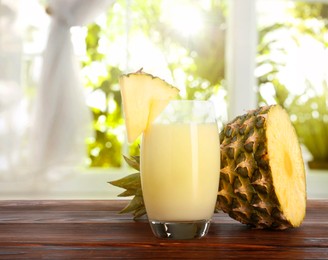 Image of Tasty pineapple cocktail or smoothie in glass and fresh fruit on wooden table indoors. Space for text