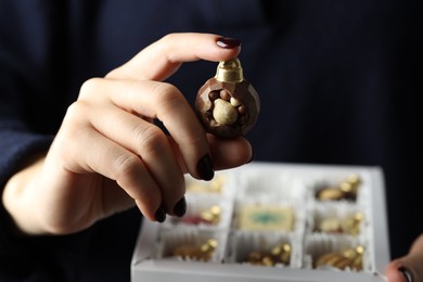 Photo of Woman holding box with tasty chocolate candies in shape of baubles, closeup