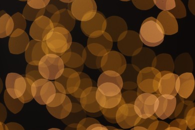 Photo of Blurred view of golden lights on black background, bokeh effect