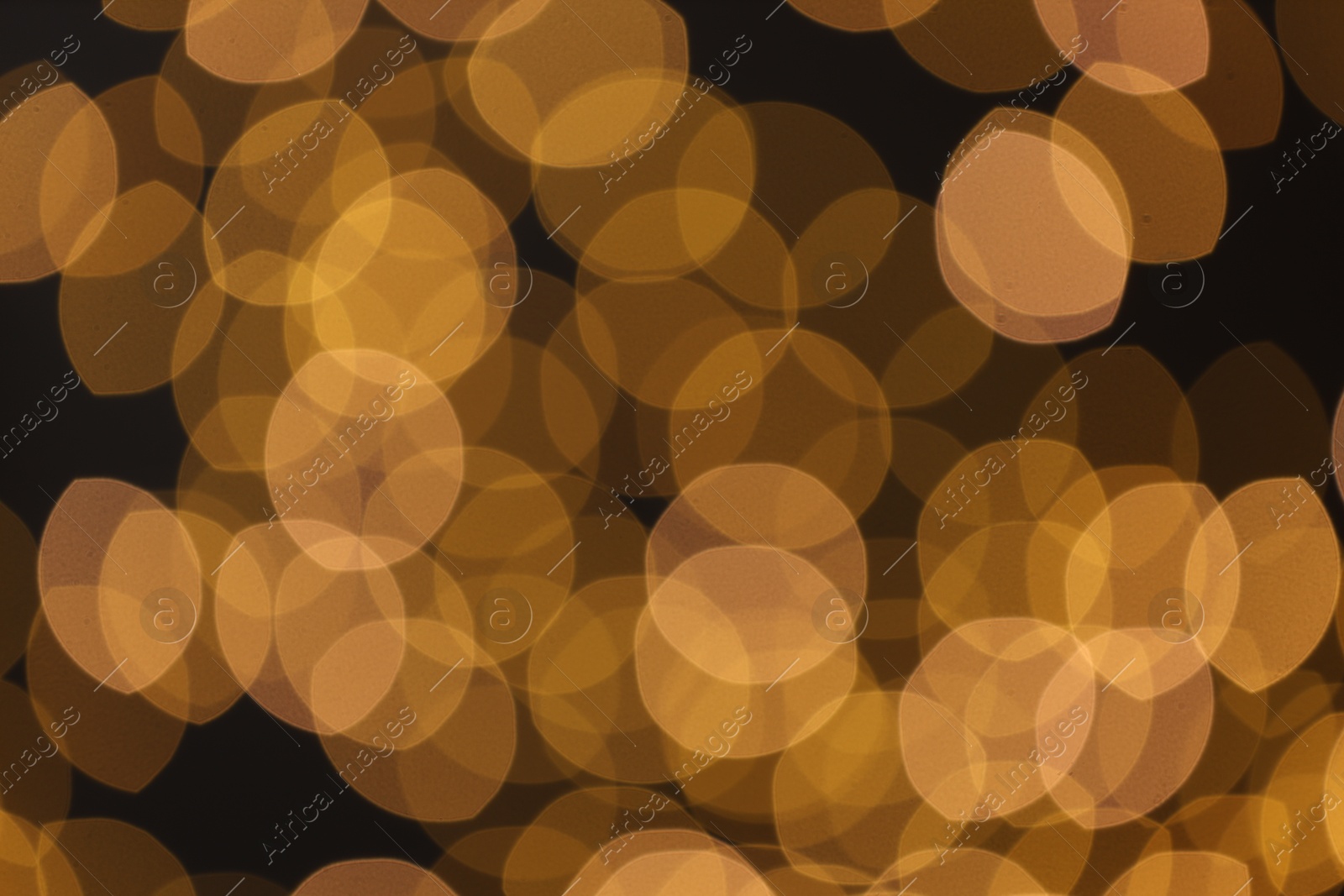 Photo of Blurred view of golden lights on black background, bokeh effect