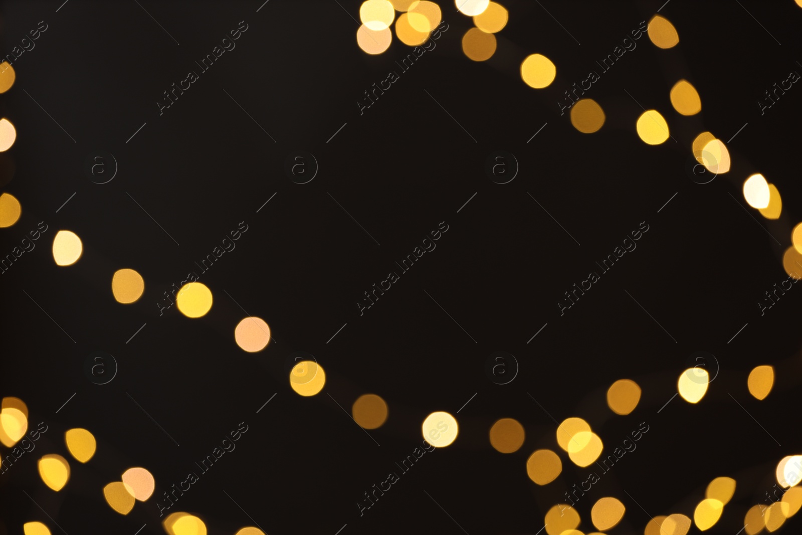 Photo of Blurred view of golden lights on black background, bokeh effect