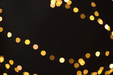 Photo of Blurred view of golden lights on black background, bokeh effect