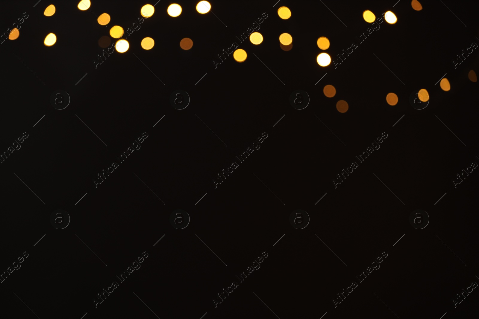 Photo of Blurred view of golden lights on black background, space for text. Bokeh effect