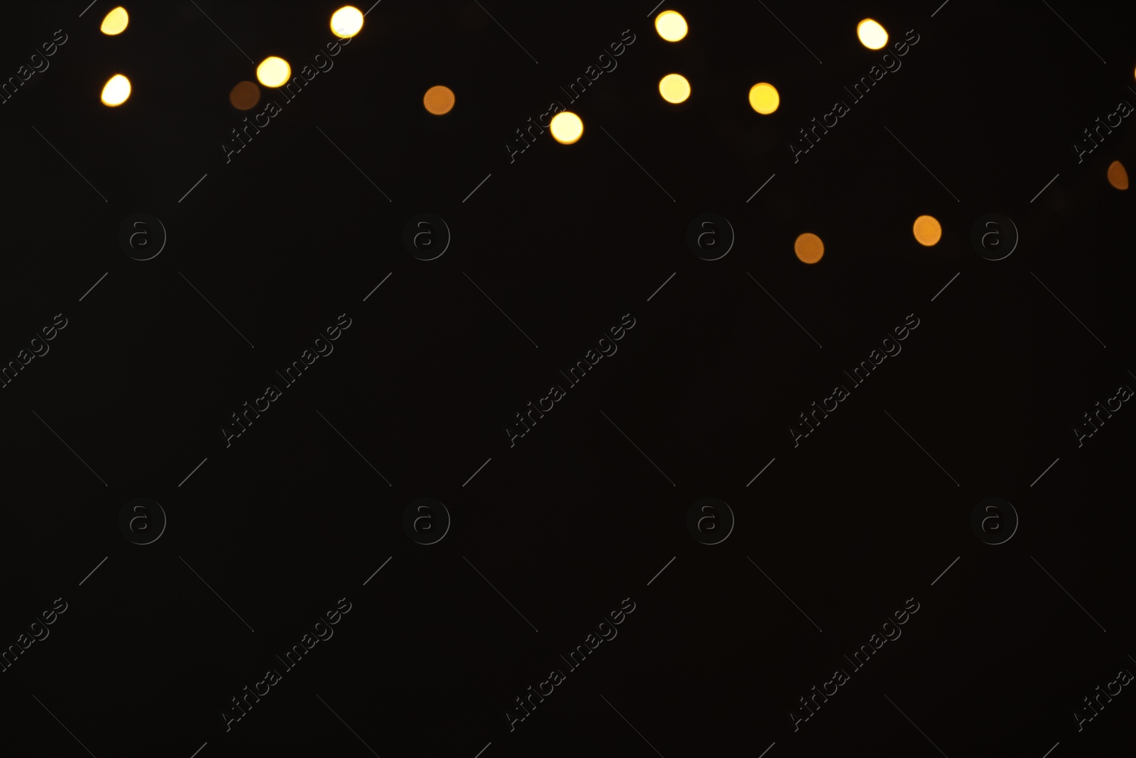 Photo of Blurred view of golden lights on black background, space for text. Bokeh effect