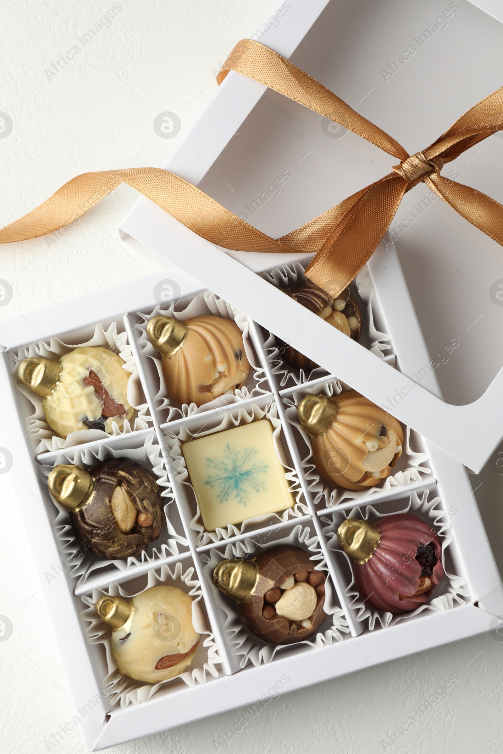 Photo of Box with tasty chocolate candies in shape of baubles on white background, top view