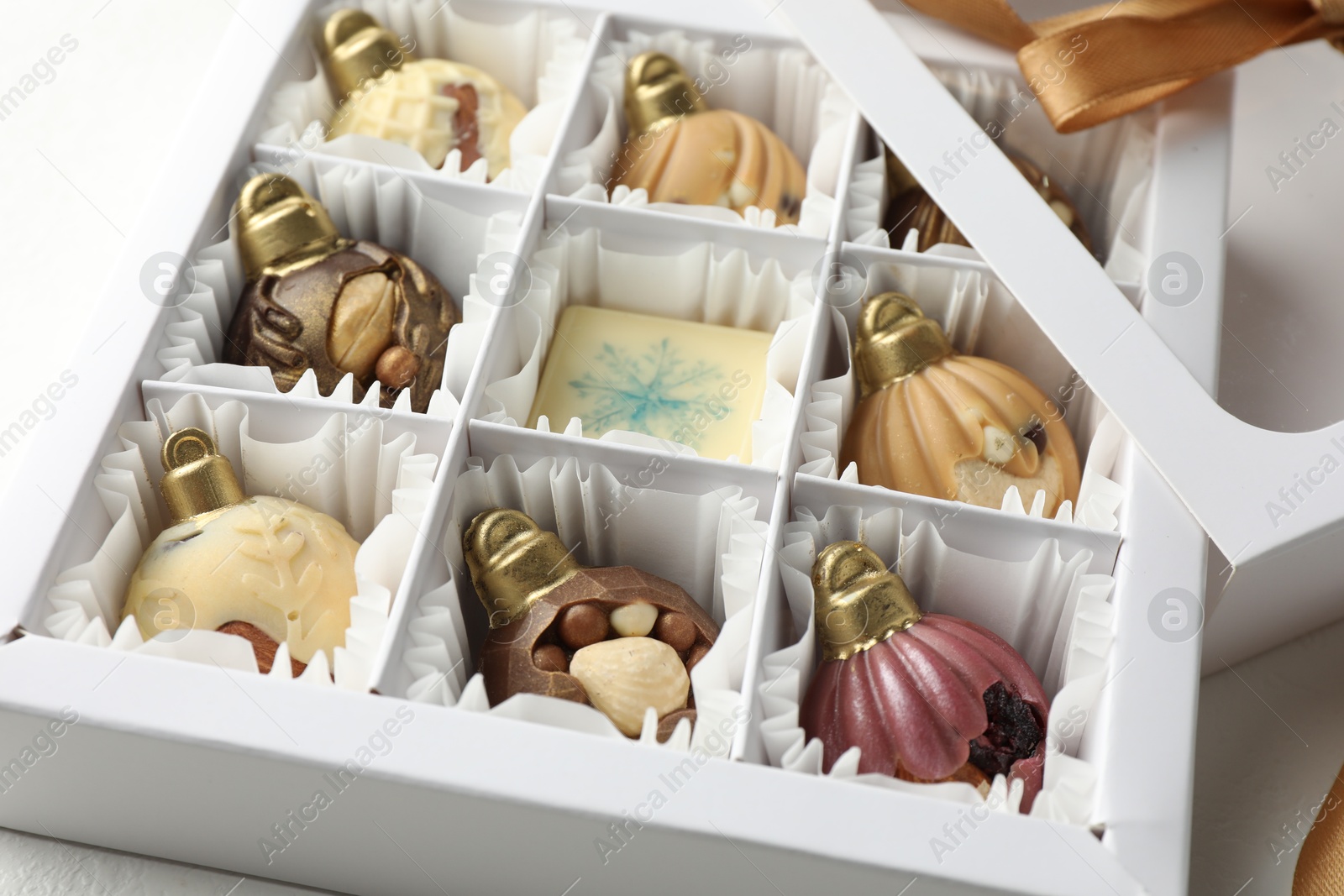 Photo of Box with tasty chocolate candies in shape of baubles on white background, closeup