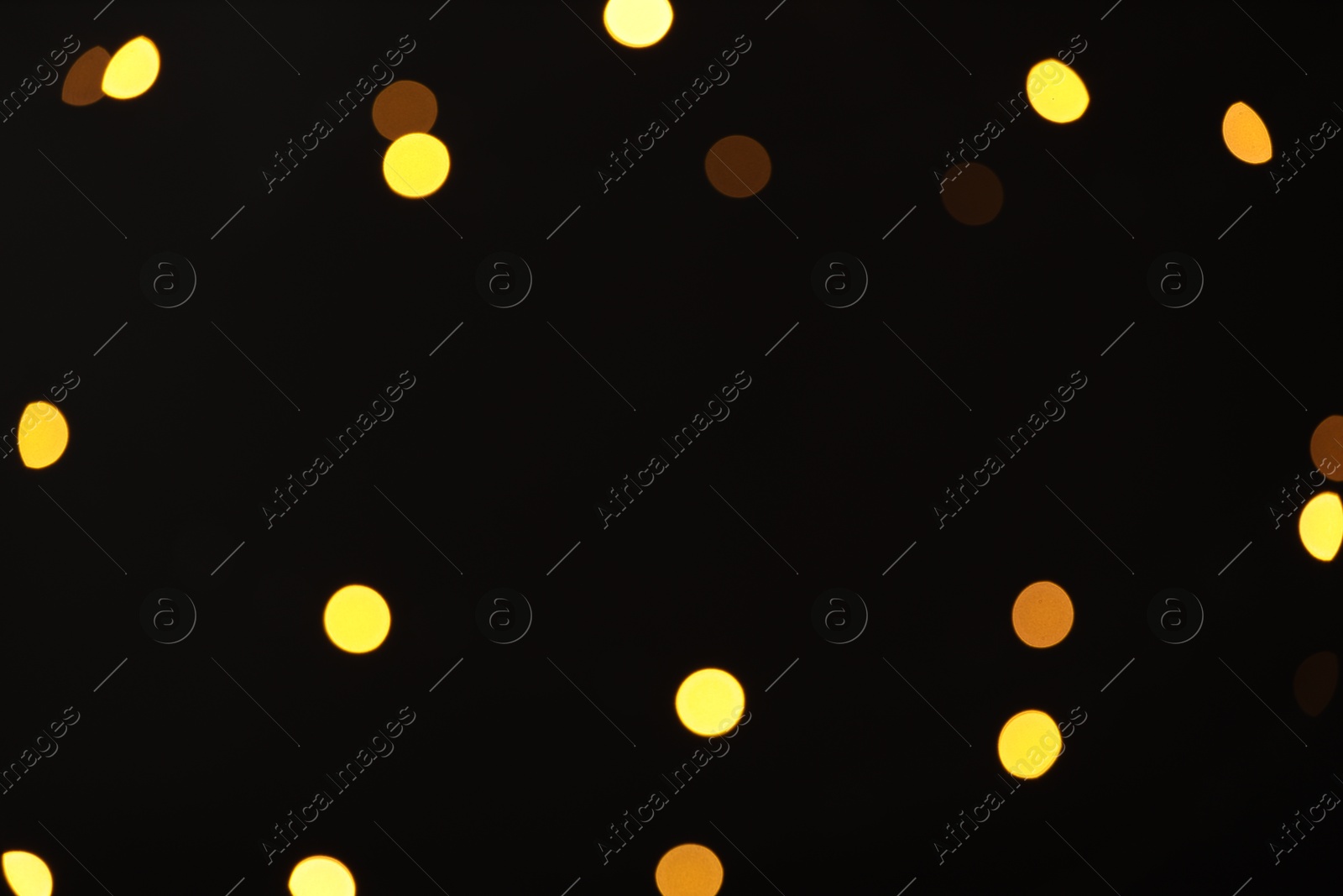 Photo of Blurred view of golden lights on black background, bokeh effect