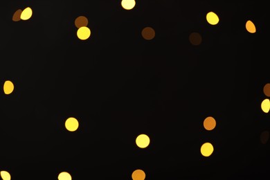 Photo of Blurred view of golden lights on black background, bokeh effect