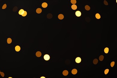 Photo of Blurred view of golden lights on black background, bokeh effect