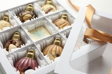 Photo of Box with tasty chocolate candies in shape of baubles on white background, closeup