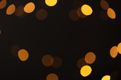 Photo of Blurred view of golden lights on black background, bokeh effect