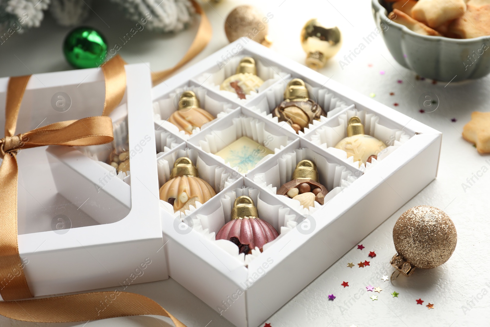 Photo of Box with tasty chocolate candies in shape of baubles and Christmas decor on white background, closeup