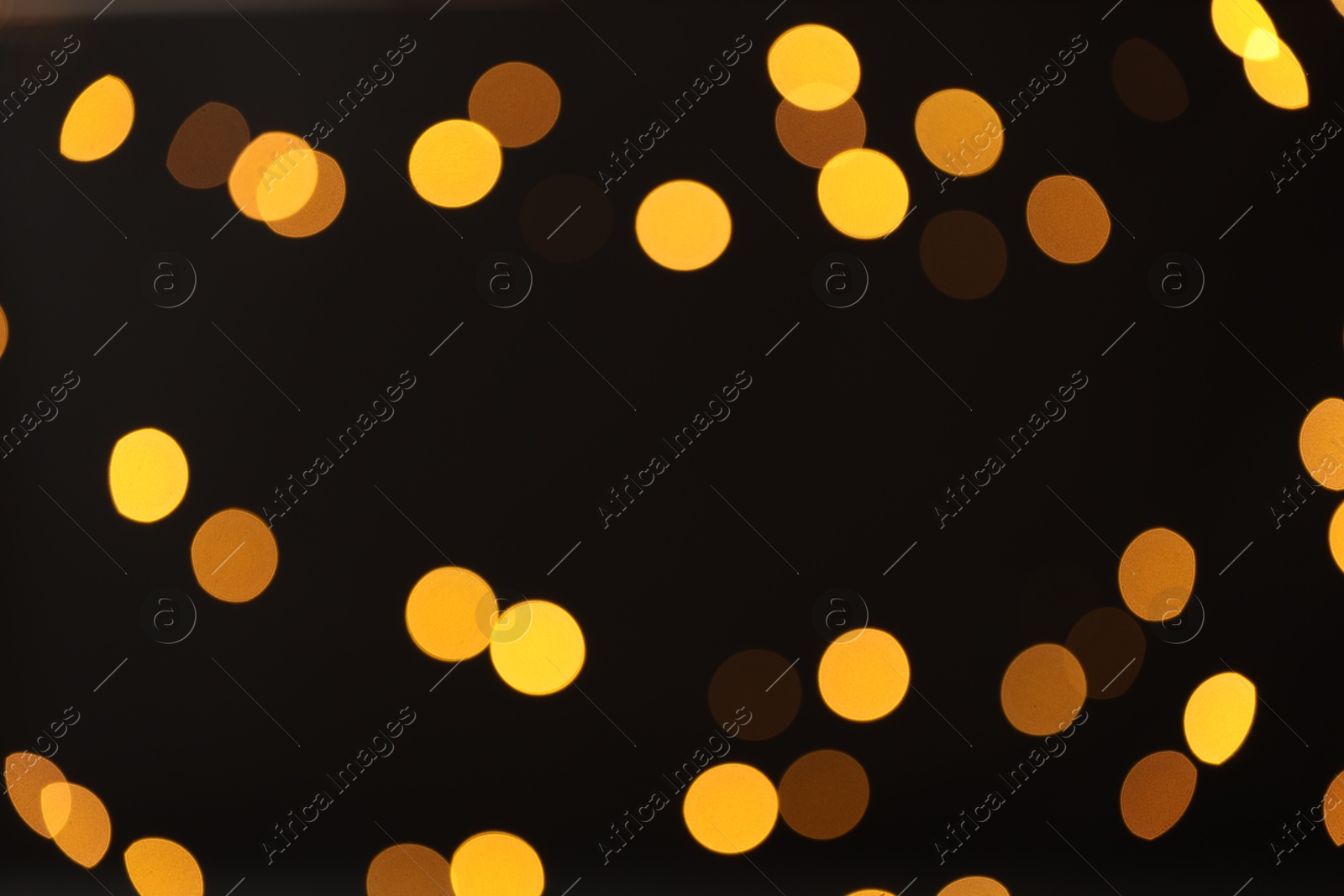 Photo of Blurred view of golden lights on black background, bokeh effect